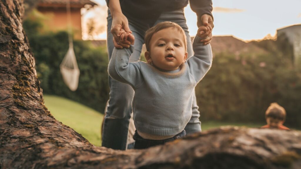 A baby boy held by his hand is learning to walk