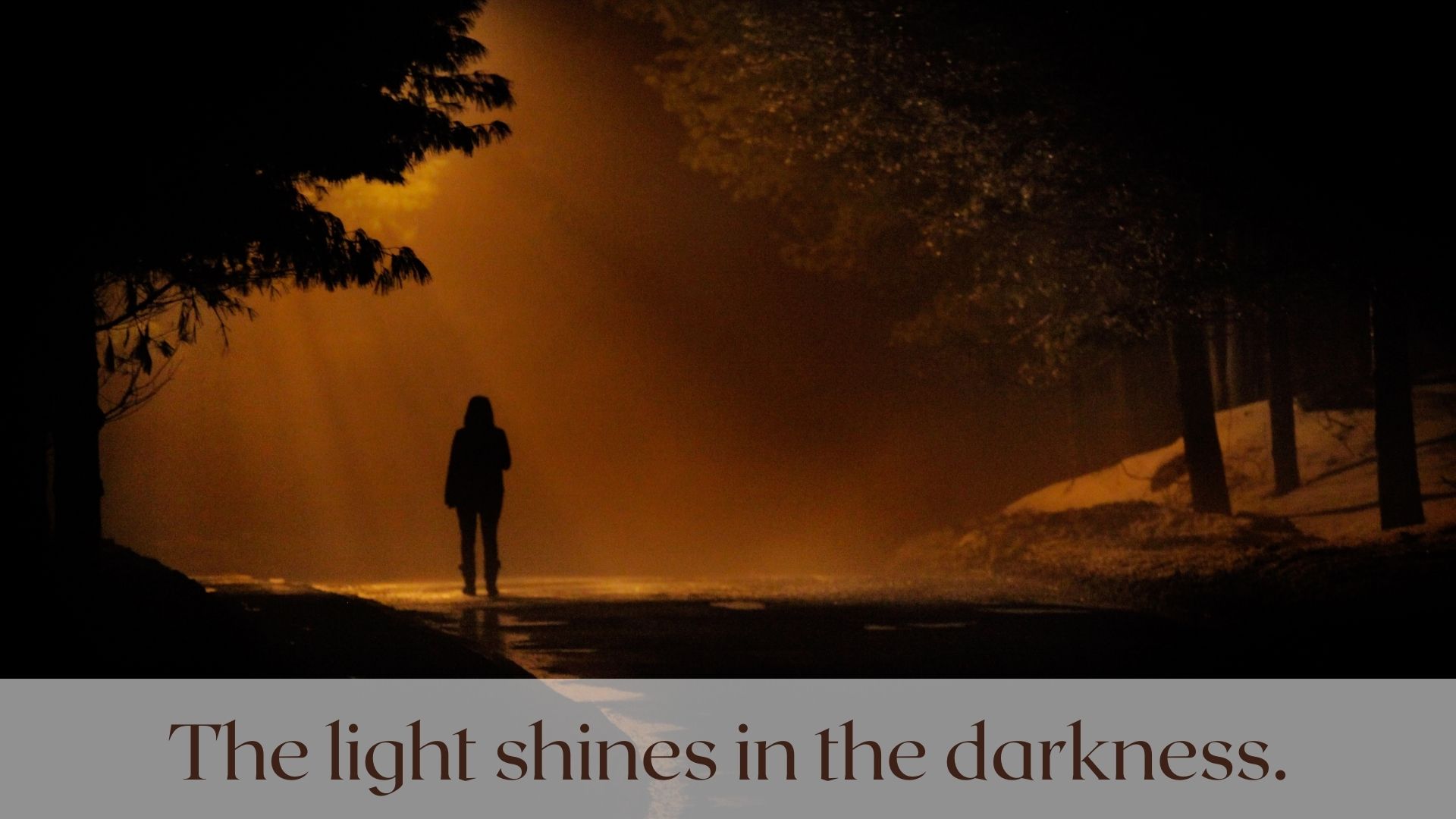A silhoutte of a lonely person walking down the street drowned in the drkness. The light shines in the darkness. John 1:5